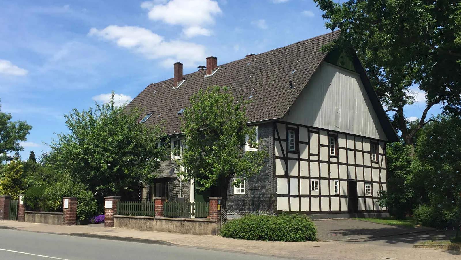Gesamtansicht des Fachwerkhauses der Zahnarztpraxis mit Garten und Zugang von der Dorfstraße