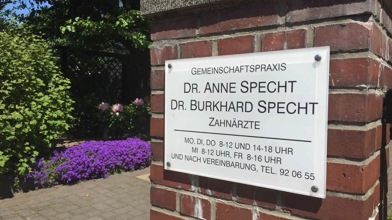 Praxisschild von Dr. Anne und Dr. Burkhard Specht am Zugang zum Garten
